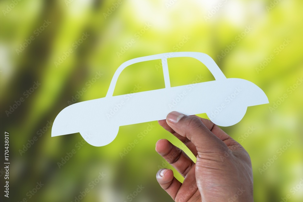 Composite image of hand holding a car in paper