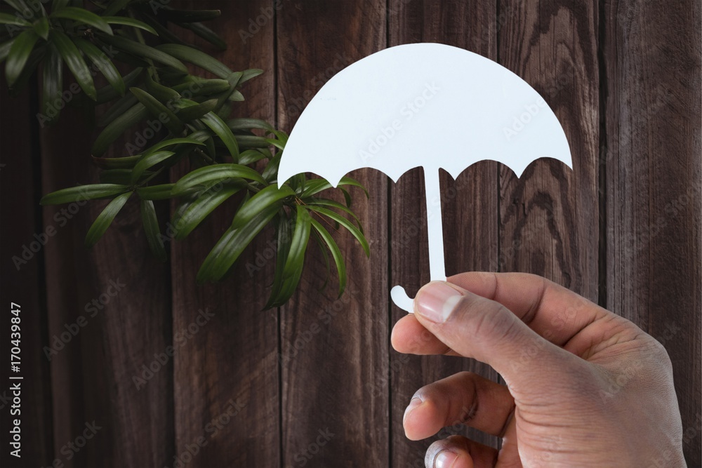 Composite image of hand holding an umbrella in paper