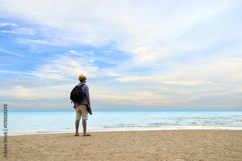 背着背包的年轻旅行者站在海边眺望大海