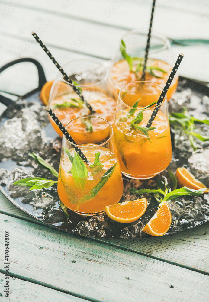 Refreshing cold alcoholic summer citrus cocktail with orange, peppermint and crushed ice in stemless