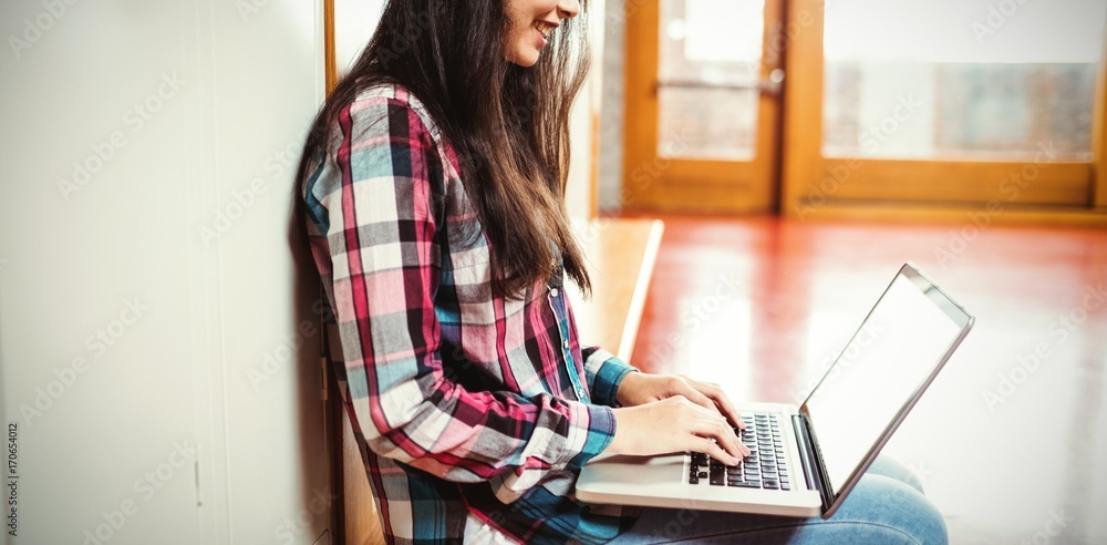 Smiling student using laptop sitting at university