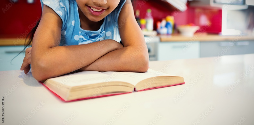 Girl reading book in kitchen