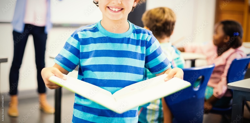 小学生拿着书站在教室里的肖像