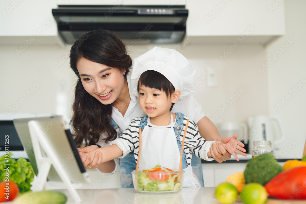 Mother with her daughter in the kitchen cooking together