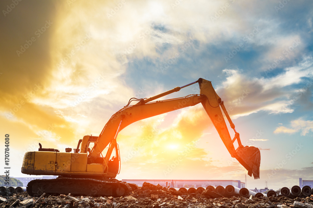 Excavator working at construction site on sunset