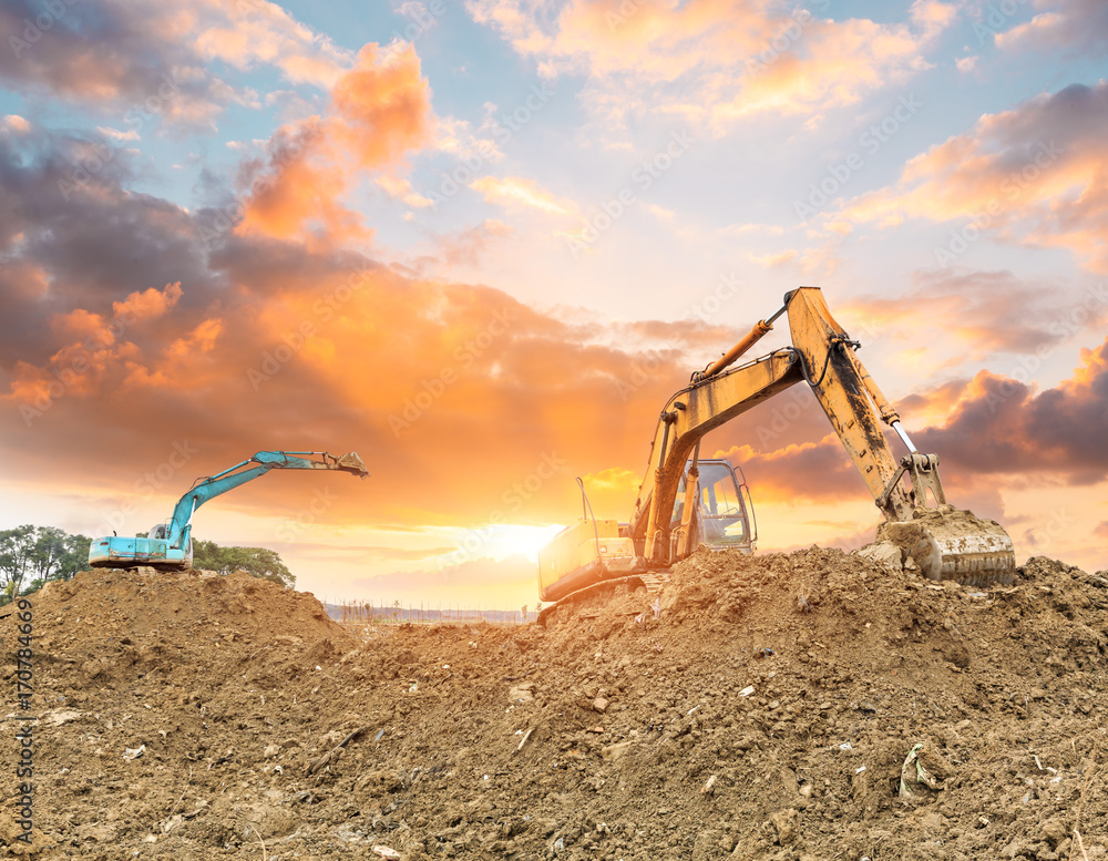 Excavator working at construction site on sunset