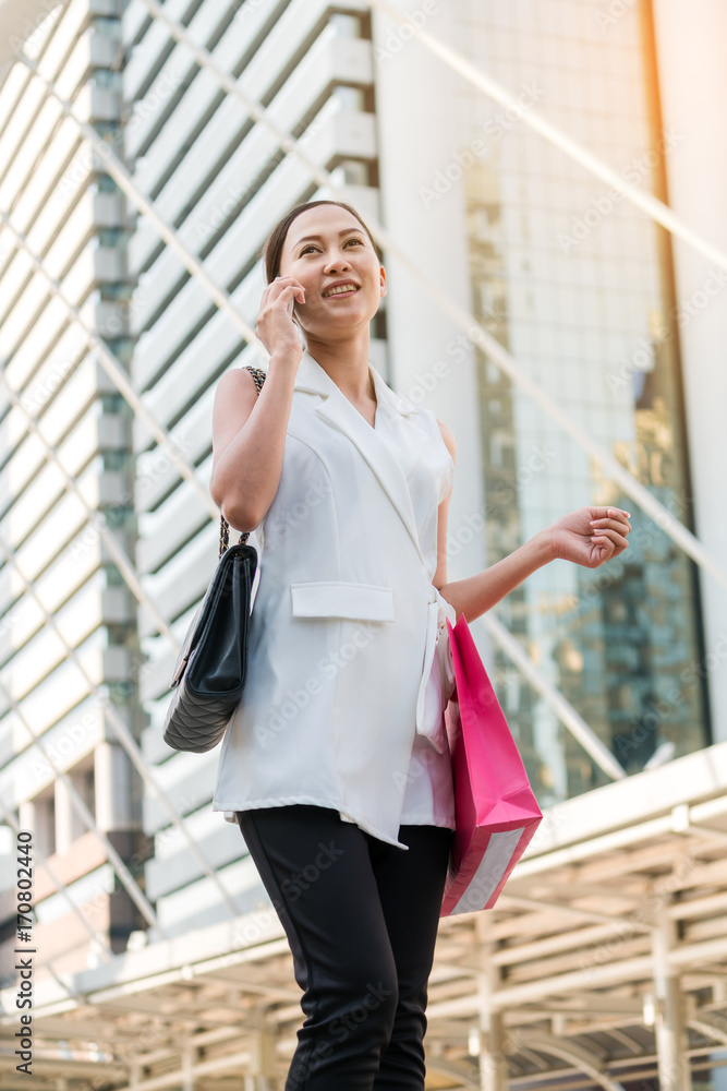 女人在打电话，手里拿着购物袋