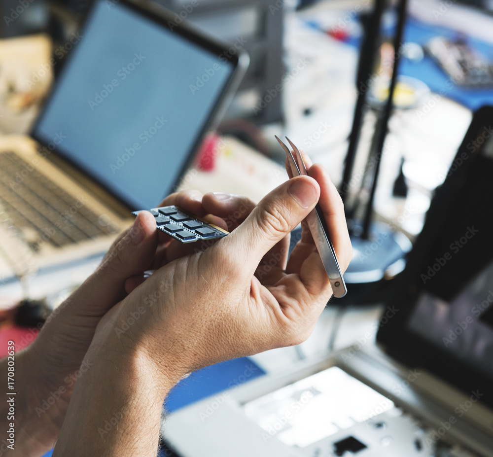 Closeup of hands holding tweezer with computer processor chips