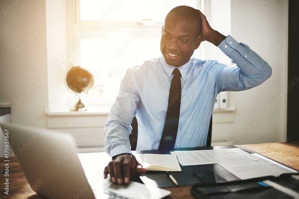 Smiling young executive working on a computer at his desk