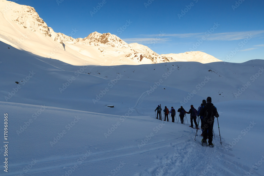 一群人穿着雪鞋徒步旅行，在奥地利斯塔拜阿尔卑斯山欣赏蓝天的山雪全景