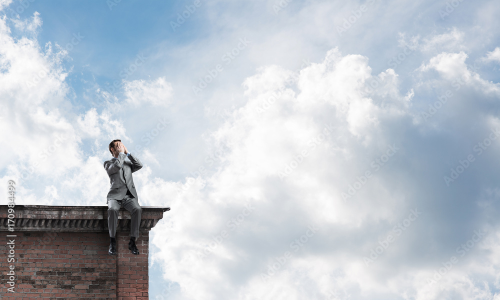 Young man on building edge do not want to see anything