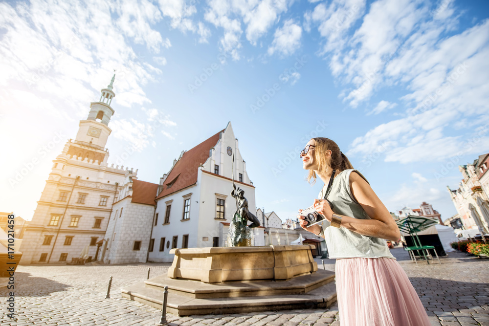 Porait of a young woman tourist traveling on the old Market sqaure in Poznan city during the morning