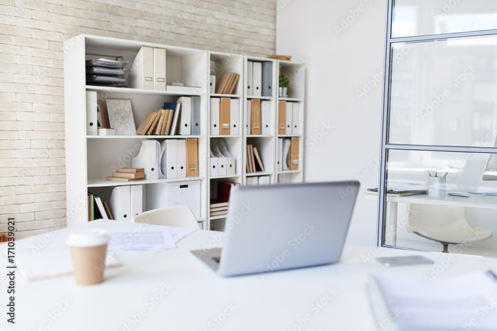 Background image of empty workplace with  laptop, coffee cup and documents on desk in office