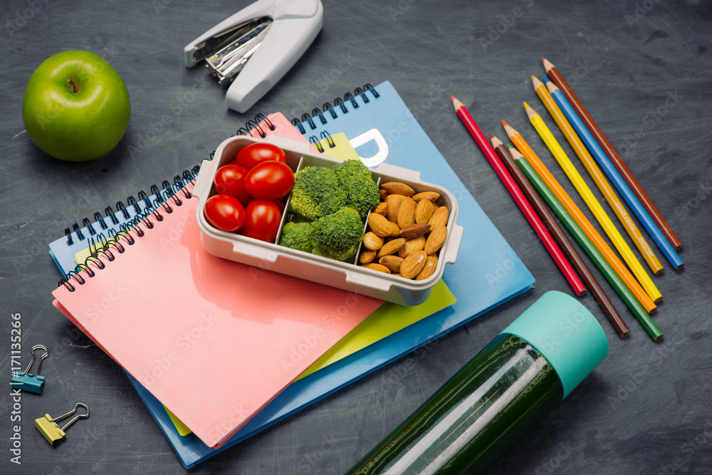 School breakfast on desk with books and pen on board background