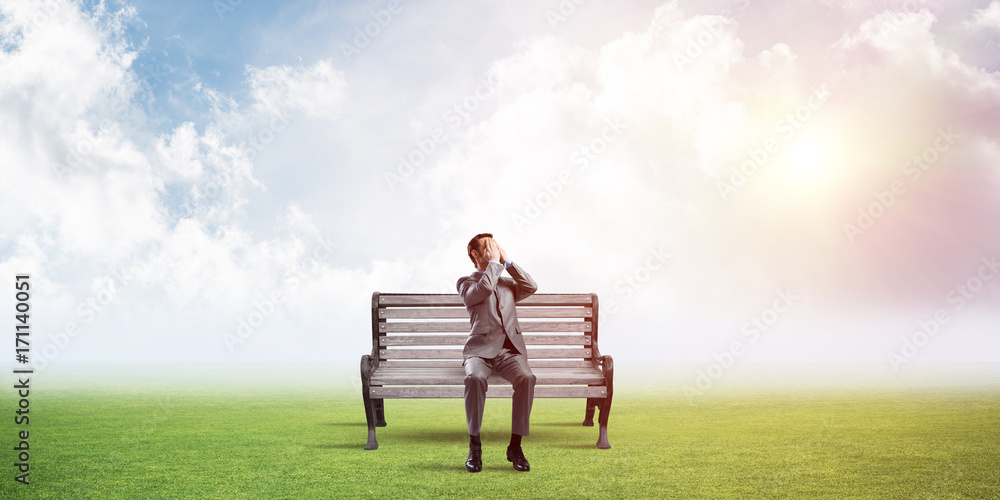 Young man in summer park on bench do not want to see anything