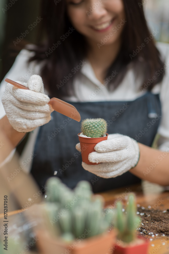 亚洲年轻女孩在花盆里种植小仙人掌的肖像