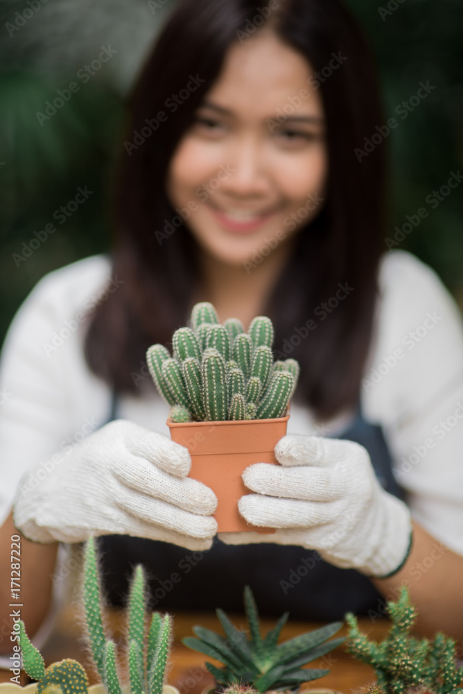 年轻的亚洲女孩拿着小仙人掌在锅里的肖像