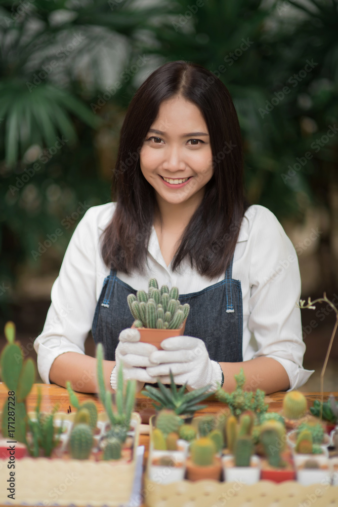 年轻的亚洲女孩在花盆里种植小仙人掌的肖像