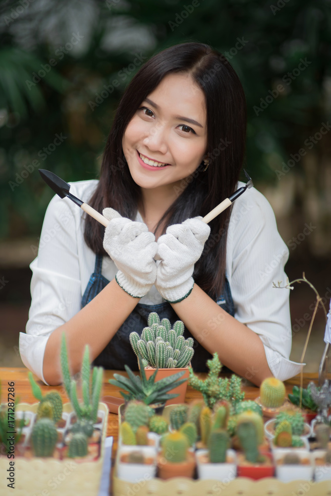 亚洲年轻女孩在花盆里种植小仙人掌的肖像