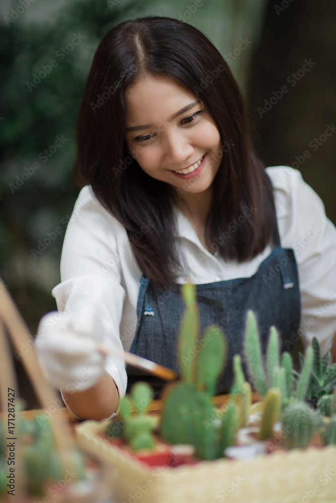 年轻的亚洲女孩在花盆里种植小仙人掌的肖像