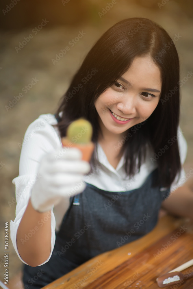 亚洲年轻女孩在花盆里种植小仙人掌的肖像