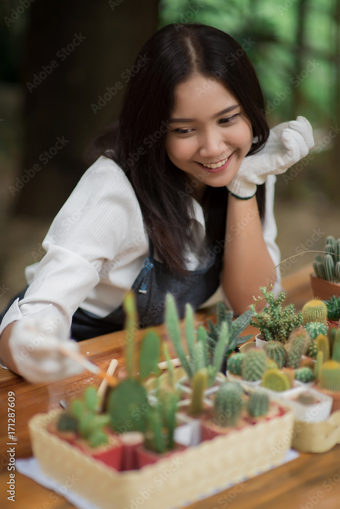 年轻的亚洲女孩在花盆里种植小仙人掌的肖像