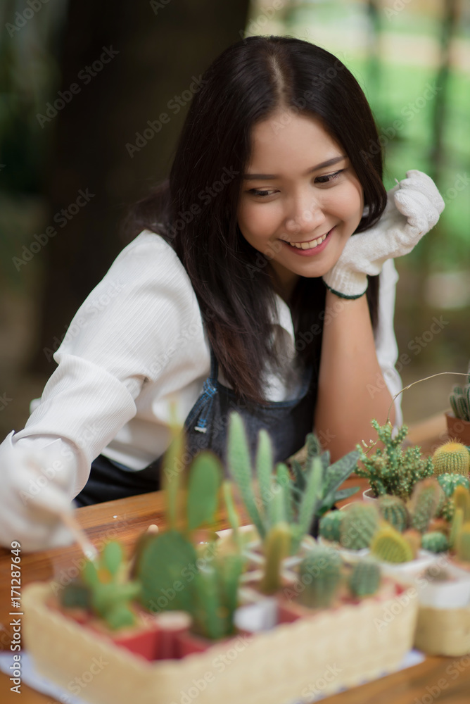 亚洲年轻女孩在花盆里种植小仙人掌的肖像