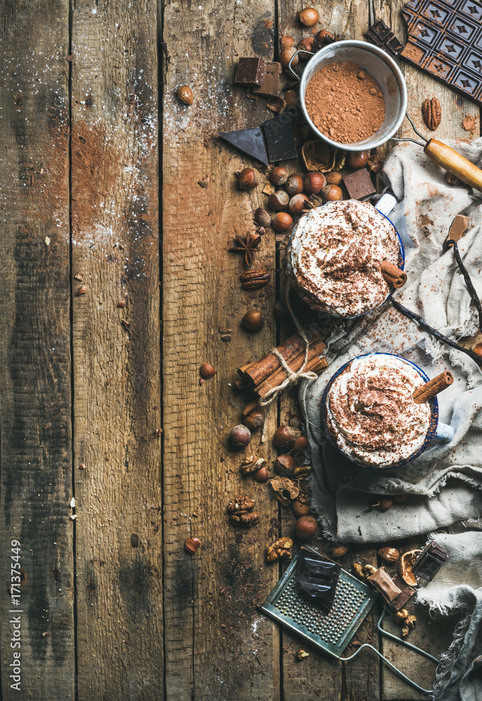 Hot chocolate with whipped cream and cinnamon sticks served with anise stars, different nuts and coc