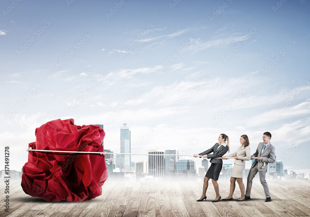 Young business people outdoors and huge paper ball as symbol of creativity