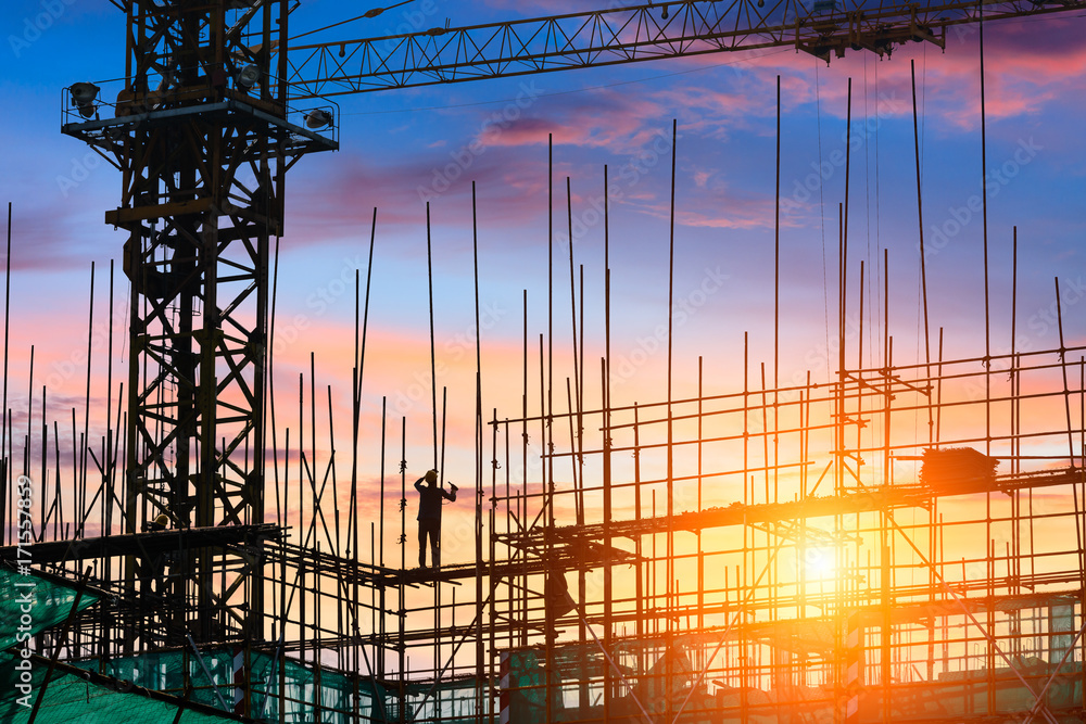 Construction site with crane and workers at sunset