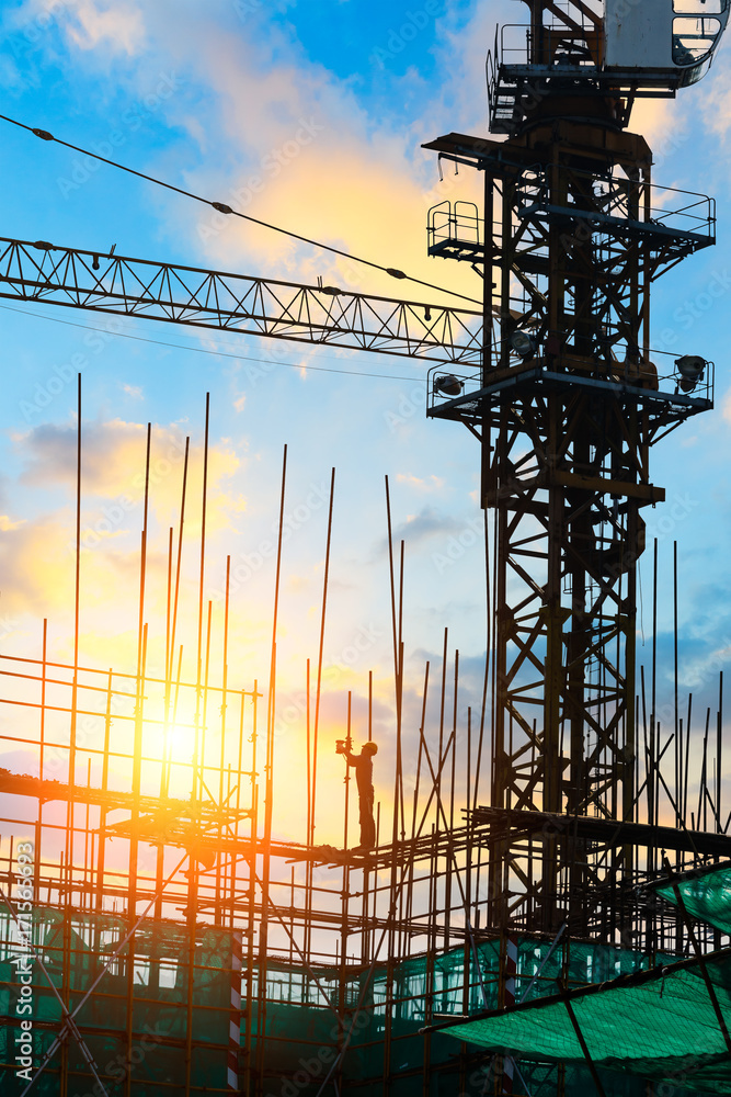 Construction site with crane and workers at sunset