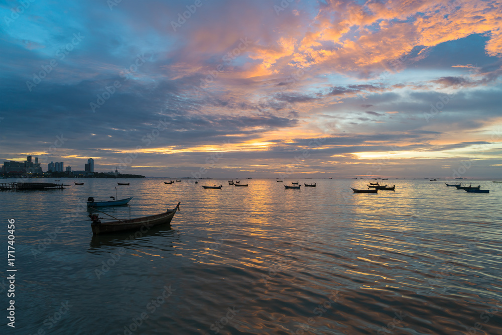 Many Thai fishing boat mooring in sea near Pattaya, Thailand at sunset.