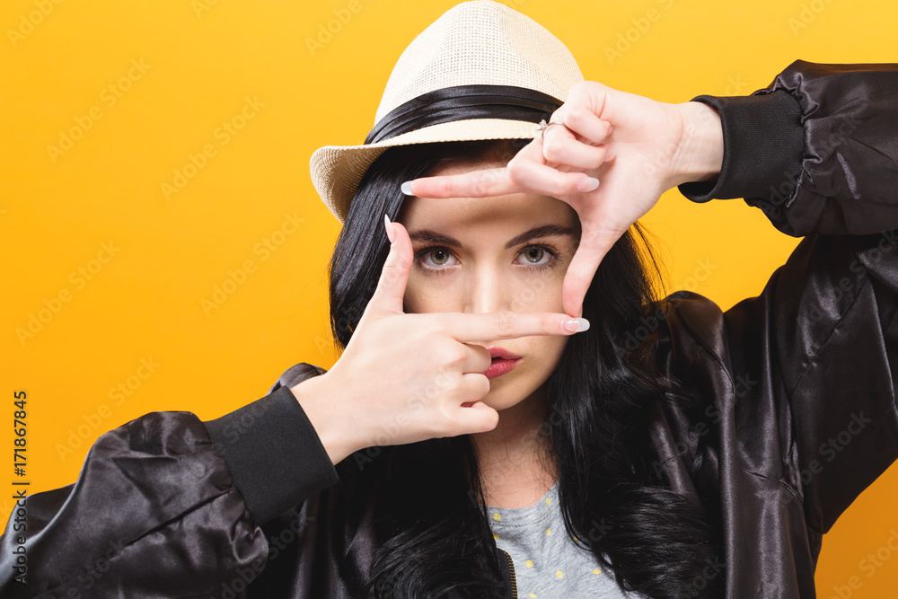  Young woman framing her face with her fingers on a solid background