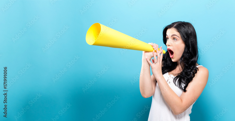 Young woman holding a paper megaphone on a solid background