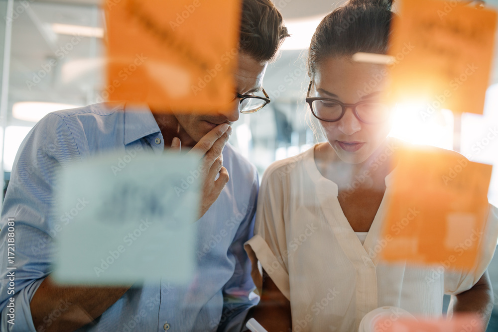 Business professionals standing behind the glass wall with sticky notes