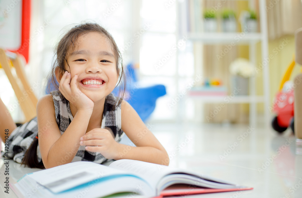 Cute  asian girl  reading a book and smiling teeth  white  while  in the live room.