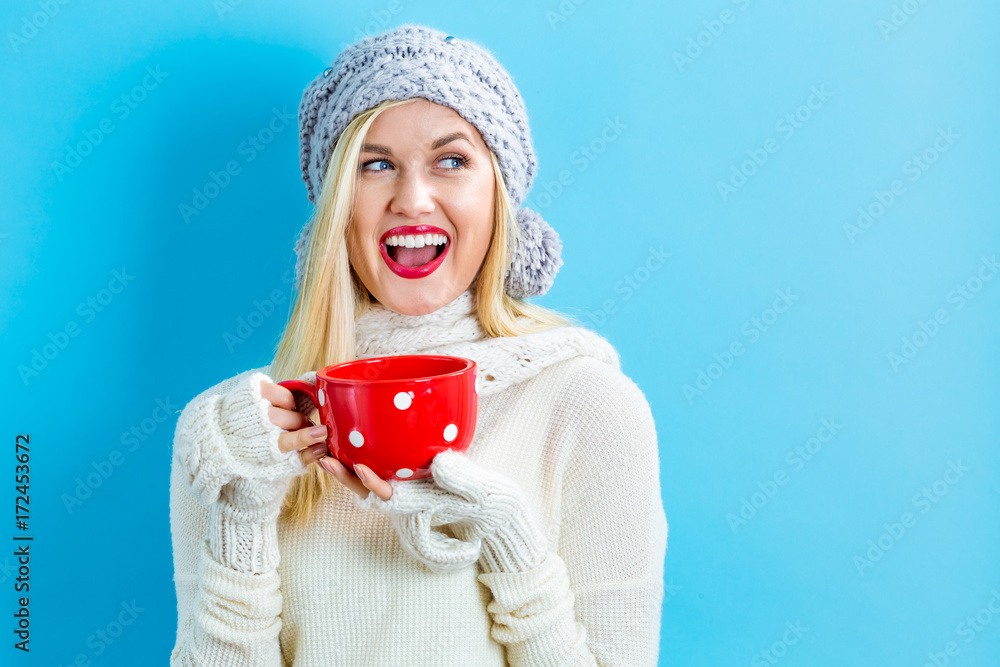 Happy young woman in winter clothes drinking coffee