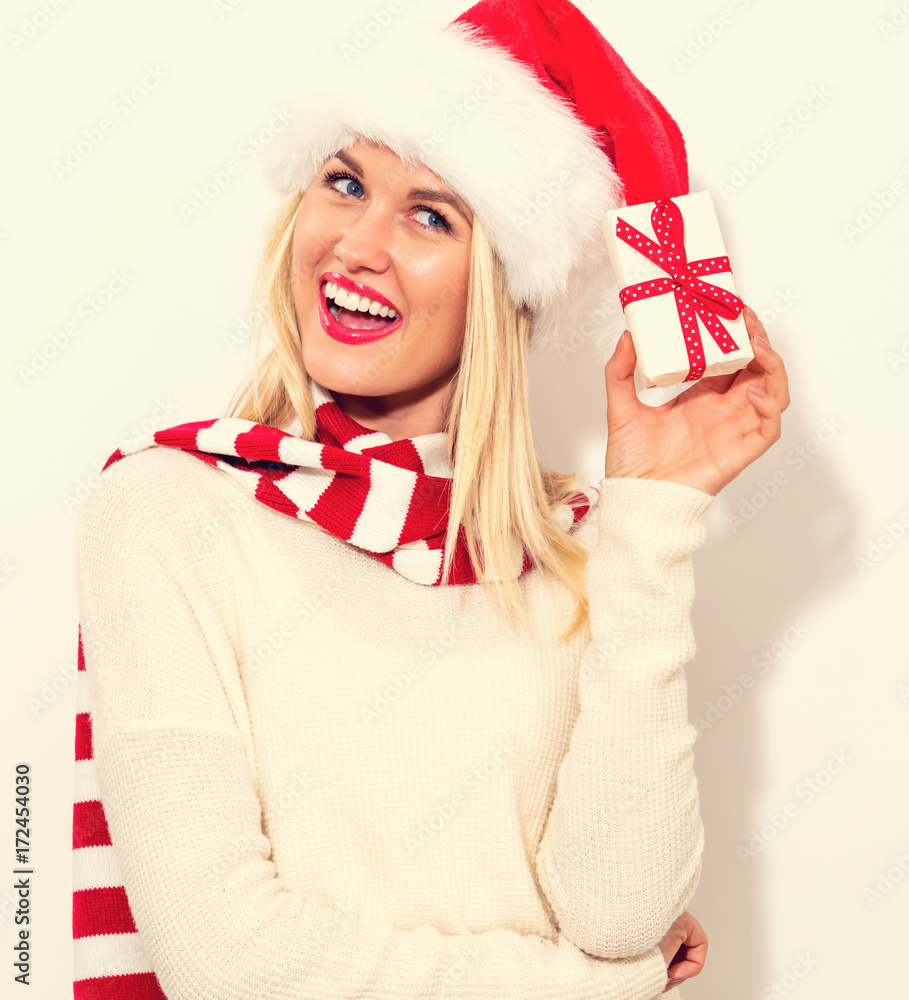 Happy young woman with Santa hat holding a Christmas present