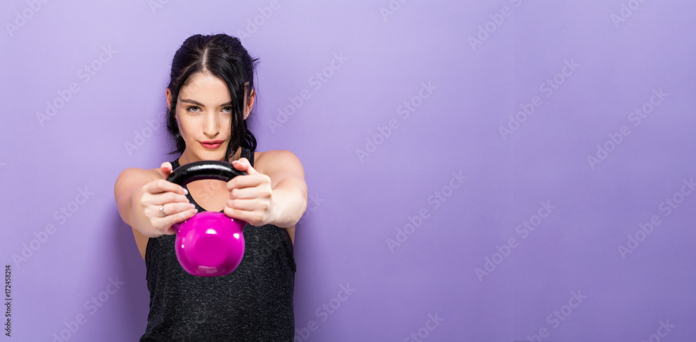 Happy young woman working out with a kettlebell