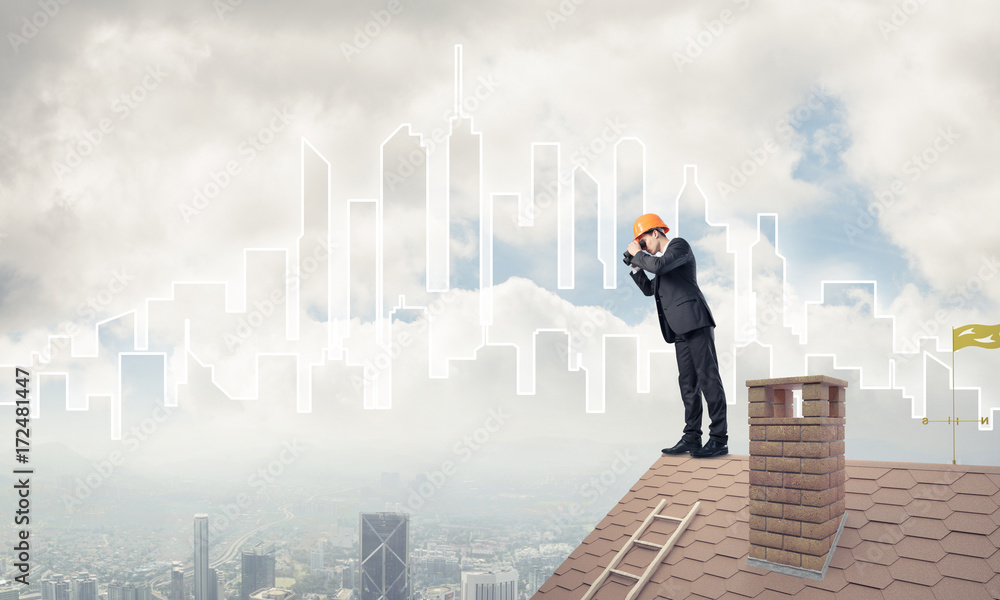 Engineer man standing on roof and looking in binoculars. Mixed m