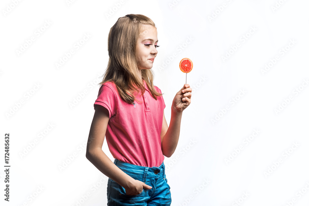 Beautiful little girl with a lollipop in hands. Happy little girl. Emotions of the child.