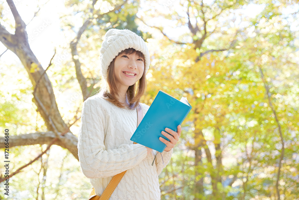 紅葉の中で読書する女性