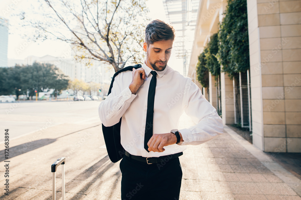 Businessman waiting outside airport and checking time