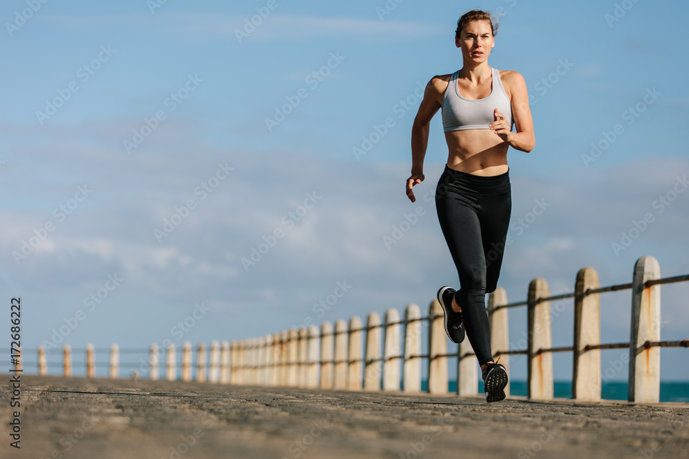 女运动员在海边的路上跑步