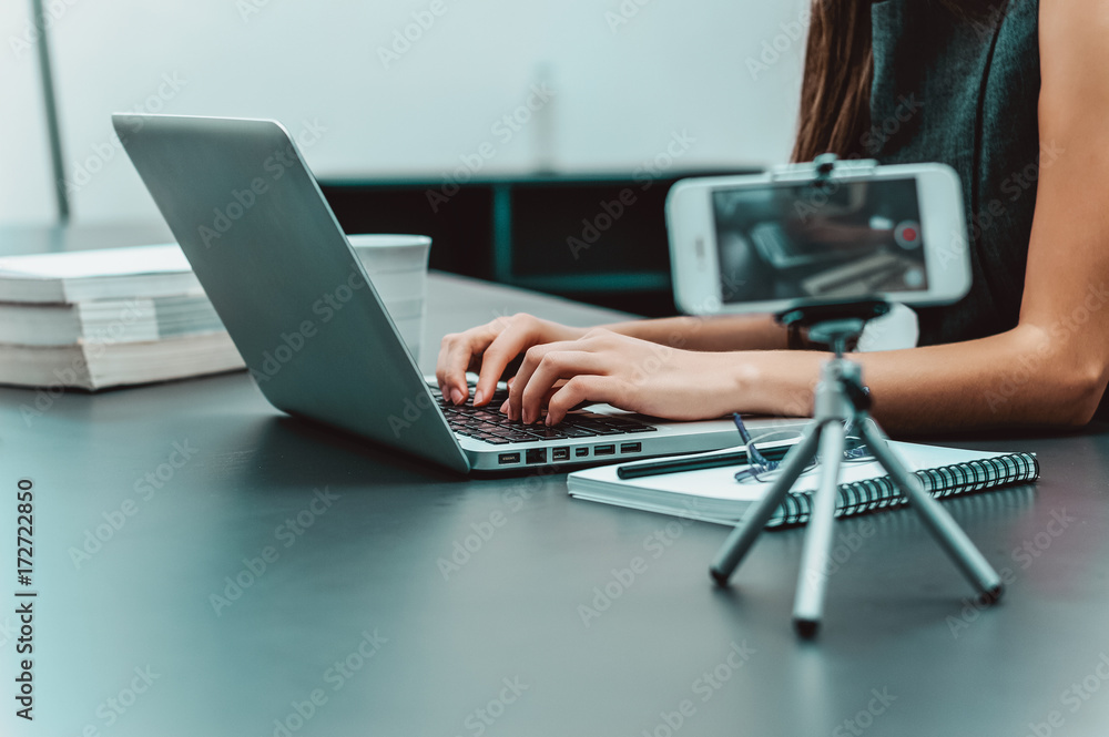 Womans hands typing on laptop while making video.