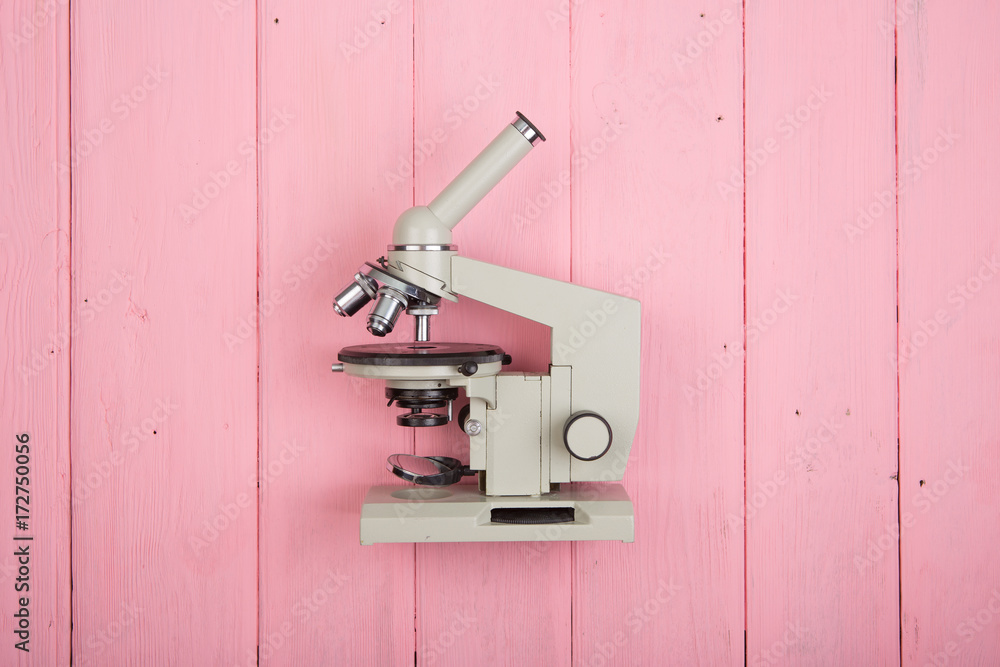 Education concept - microscope on the pink wooden desk