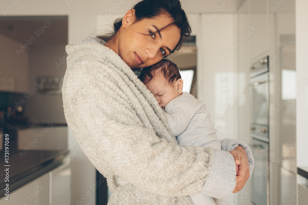 Young woman carrying her newborn baby boy