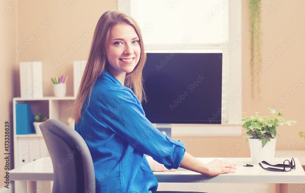 Happy young woman using her computer in her home office