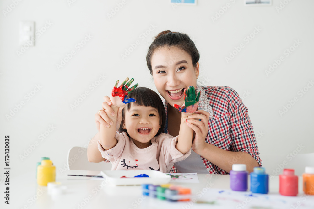 一个幸福的家庭正在画画。妈妈帮女儿画画