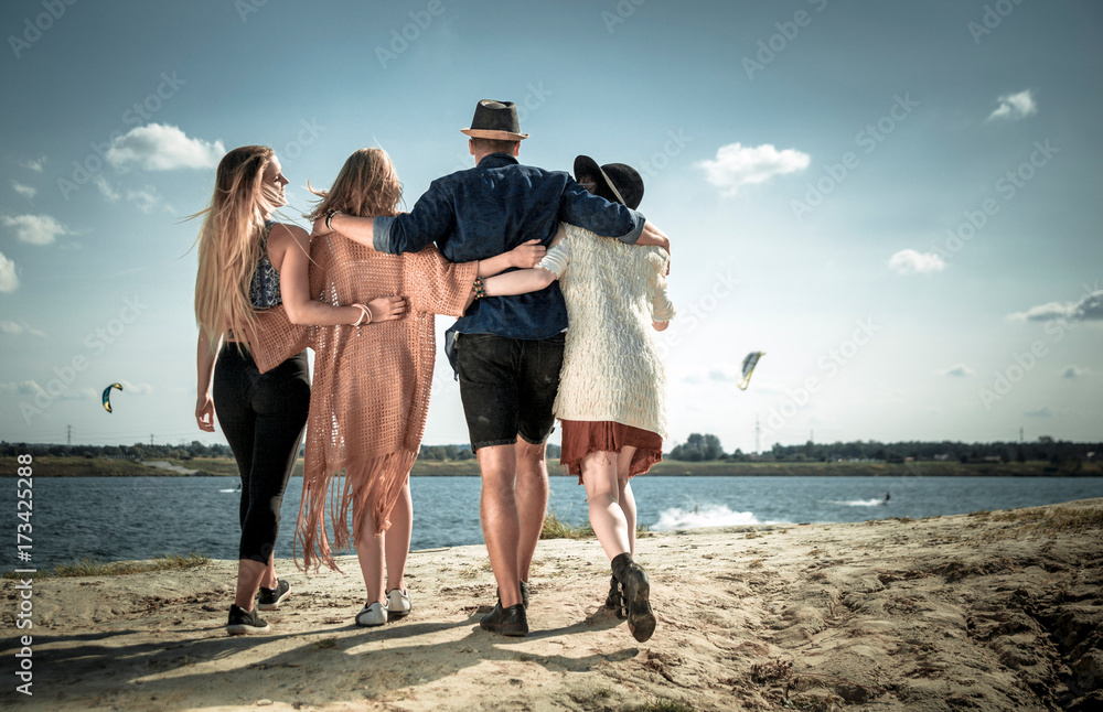 Group of happy friends walking on beach, positive mood